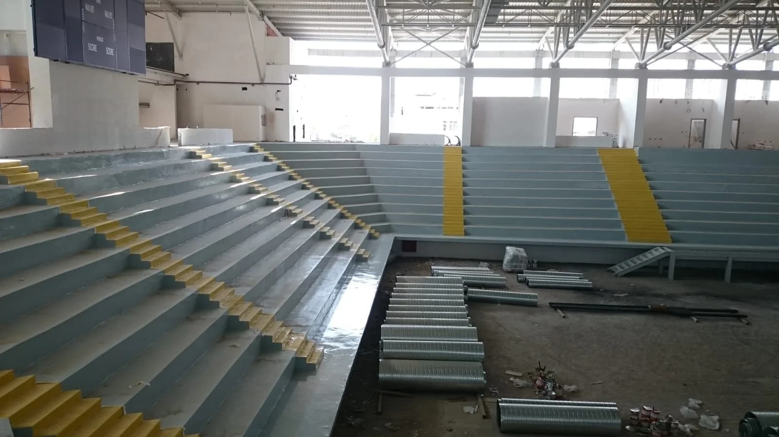 Spor salonu tribün basamaklarına uygulanmış epoksi kaplama ve sarı kaymaz şeritler